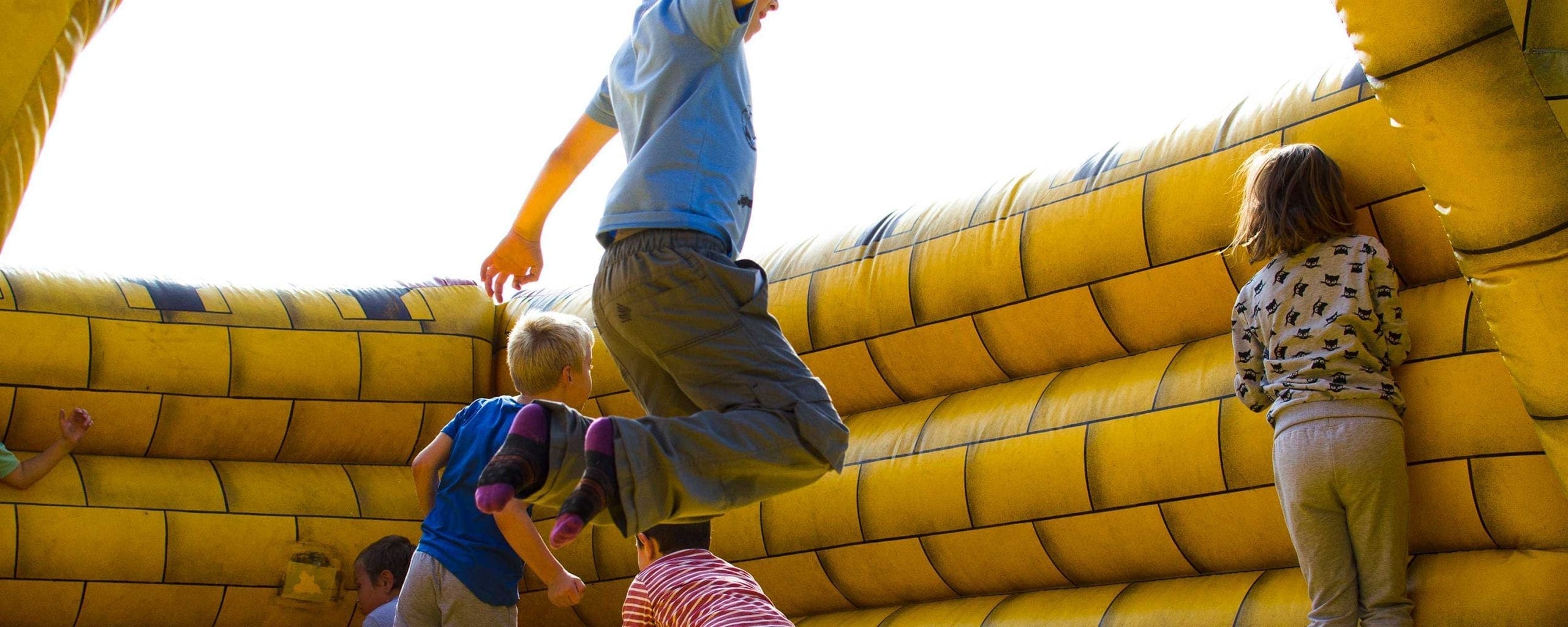 hero-inflatable-3000×1200 kids having fun at an event on an inflatable moon bounce bounce house