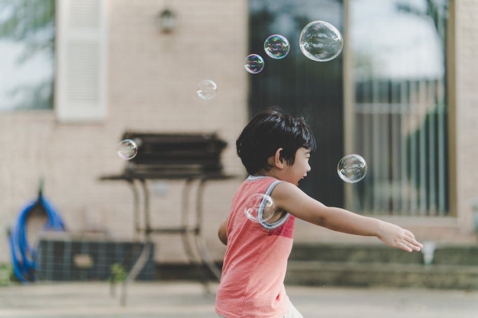 Kid blowing bubbles at an outdoor bbq event
