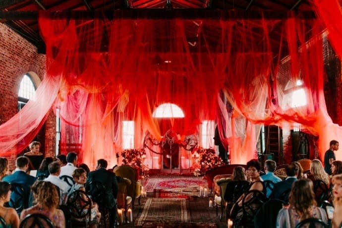 Wedding with red sheer draping and vintage carpet