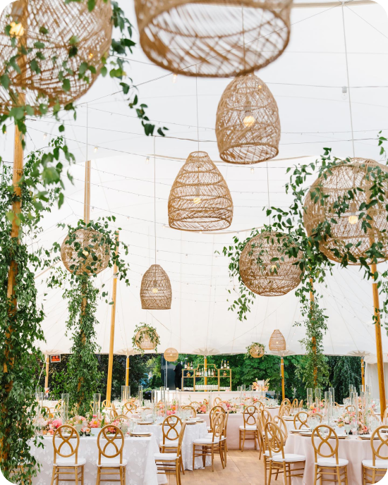 Lámparas colgantes de ratán en capas —redondas, en forma de cúpula, en forma de lágrima— dispuestas en diferentes alturas y suavizadas con plantas trepadoras, todo ello bajo una carpa de lona en la Marble House de Newport.