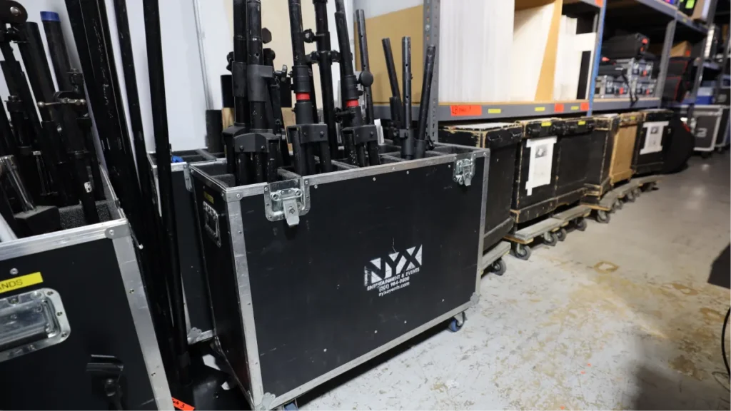 Rows of organized audio, video, and lighting equipment in an event production warehouse