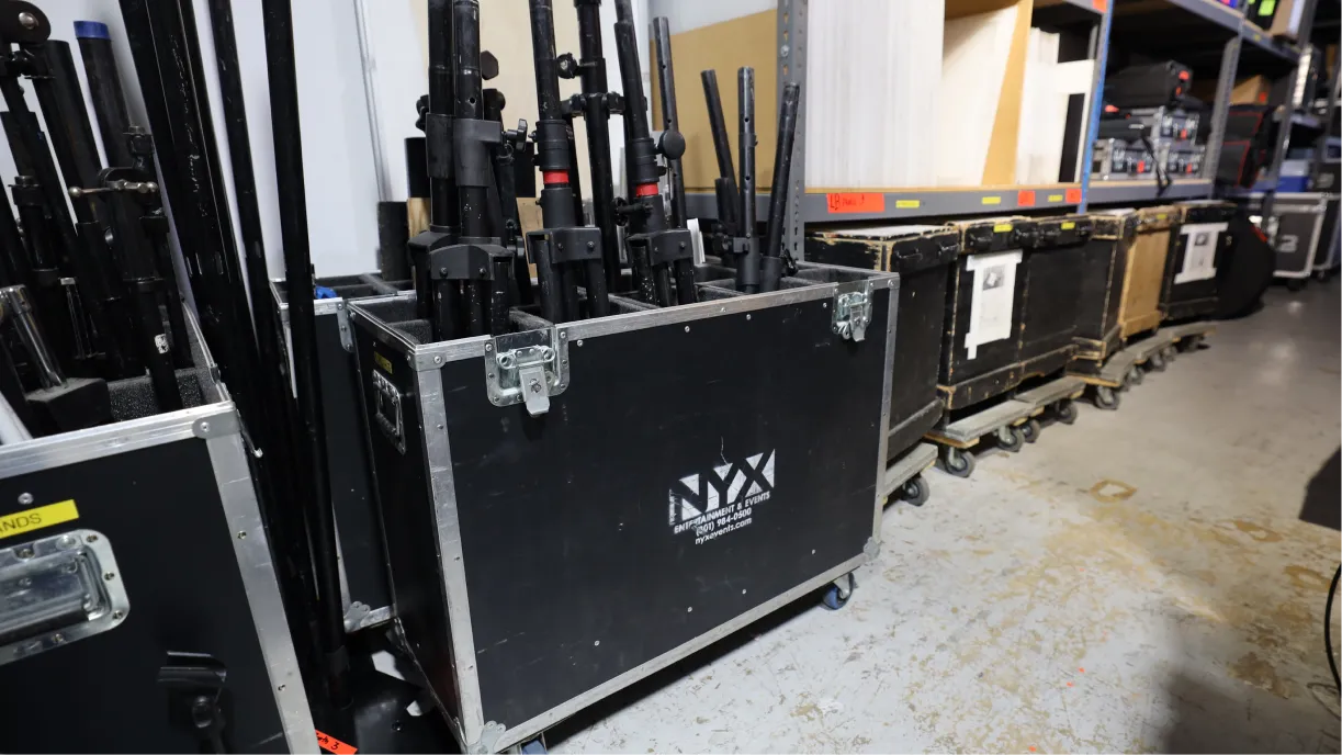 Filas de equipos de audio, vídeo e iluminación ordenados en un almacén de producción de eventos