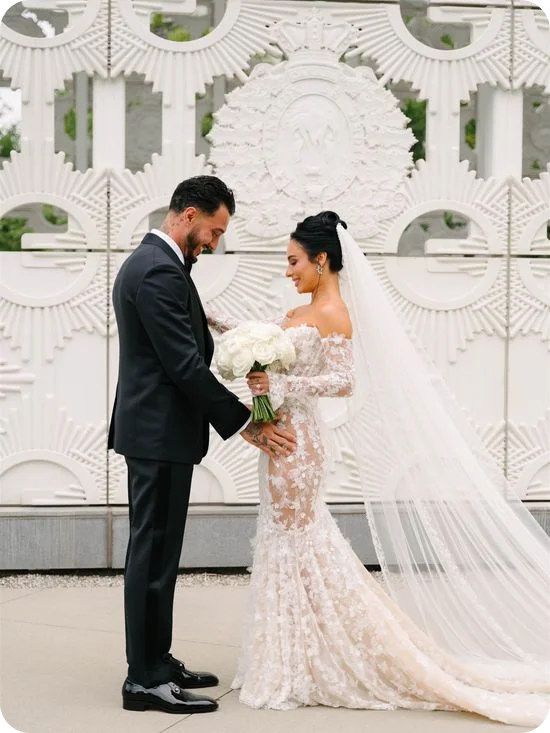A circular floral arch framing an event entrance, with crystal chandeliers overhead and white calla lilies spilling onto the floor