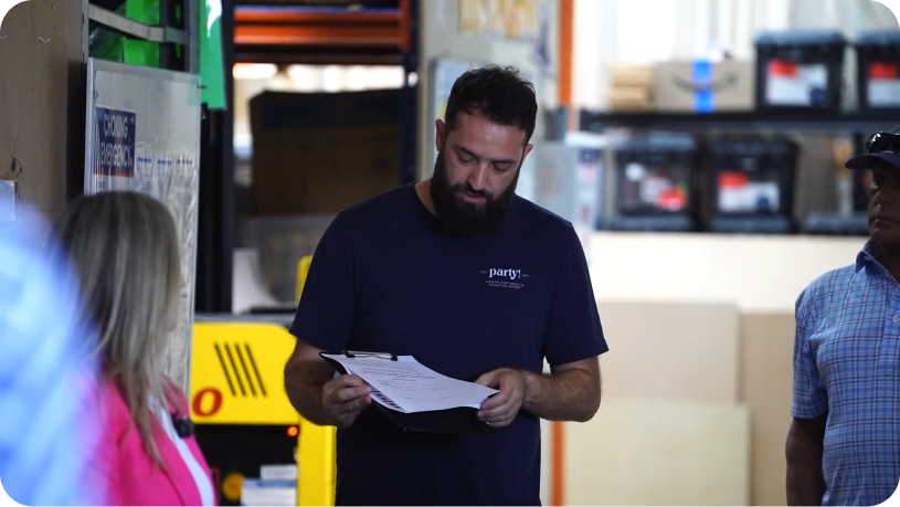 Crew member reviewing a printed order form on a clipboard in the event rental warehouse