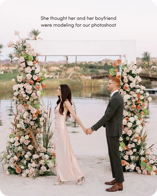 Couple holds hands between two lush floral arch pillars at a lakeside surprise proposal