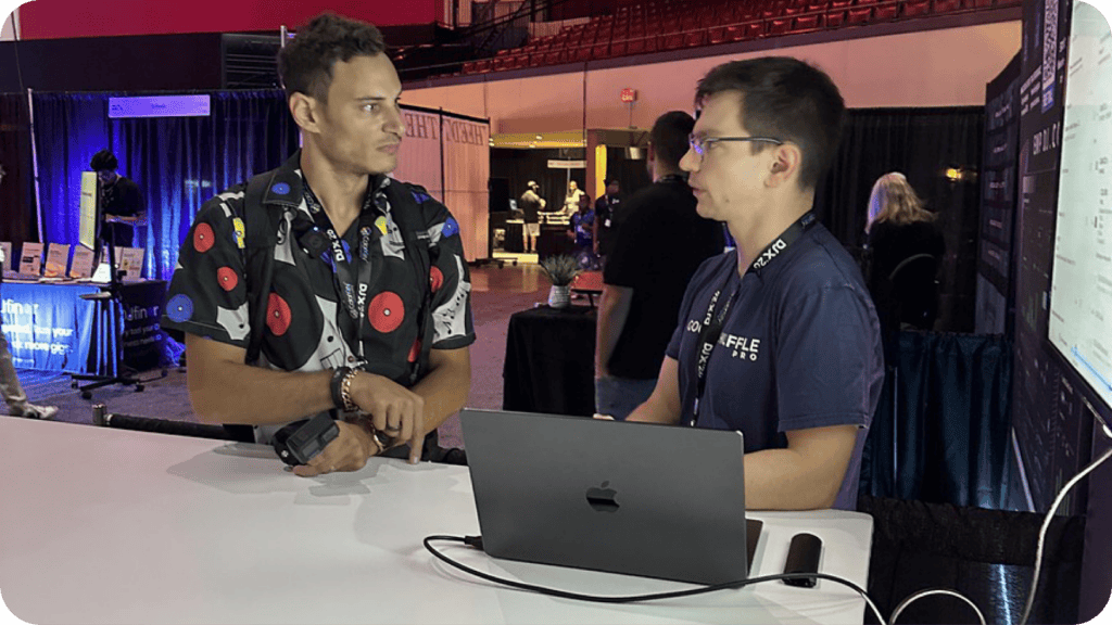 Jake Scotto of Goodshuffle Pro walking a DJX attendee through booking software on a laptop at the booth