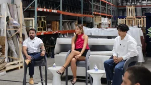 Three members of the Staging Design DC team seated for a panel discussion in their Beltsville warehouse, with pallet racks of chairs and decor behind them