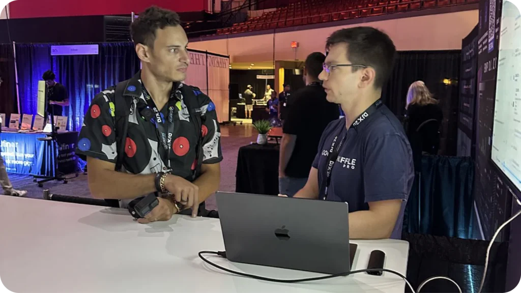 Jake Scotto of Goodshuffle Pro walking a DJX attendee through booking software on a laptop at the booth