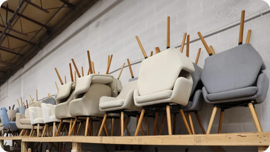 Upholstered accent chairs stored on a raised wooden shelf above lower stock in the Staging Design DC warehouse