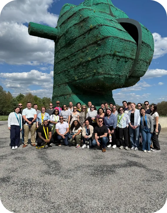 The Goodshuffle team gathered in front of a giant green sculpture
