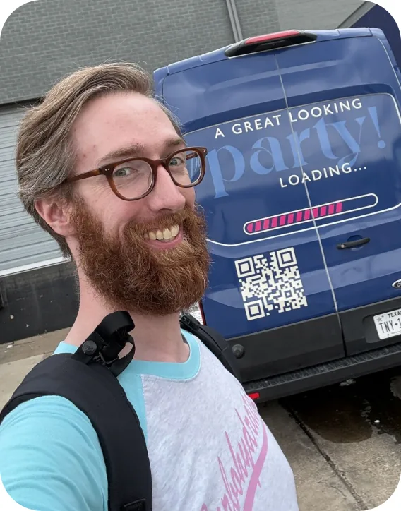 A Goodshuffle teammate taking a selfie in front of a customer's branded party rental van